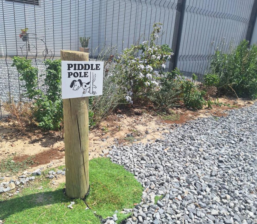 A wooden piddle pole with a cartoon sign in the salon's garden